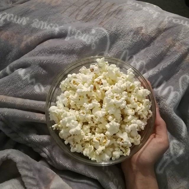 holding a bowl of popcorn while relaxing on the sofa